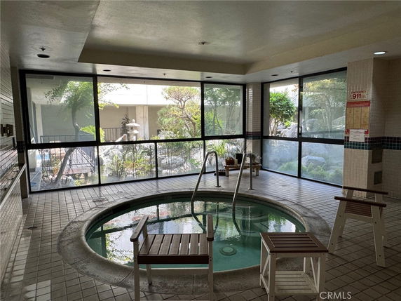 Indoor hot tub area with large windows and chairs.