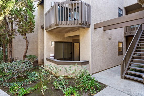 Front view of a multi-story building with a balcony and outdoor staircase.
