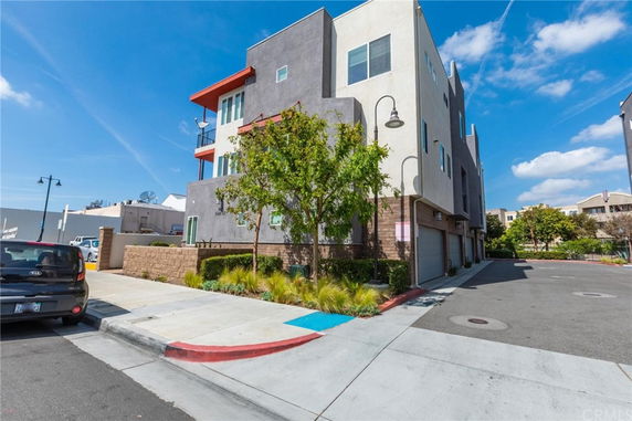 Front view of a multi-story building with modern design elements, including a red accent and multiple garages.