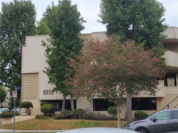 Front view of a multi-story building with trees and a number 9950 displayed.