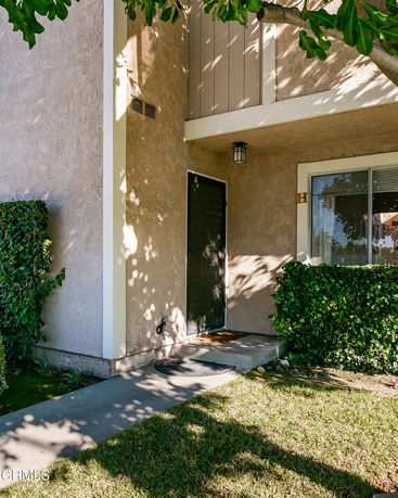 Front view of a partially visible house entrance with stucco walls and a small porch.