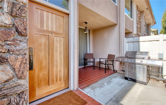 Front view of a house entrance with a wooden door and adjacent patio area.