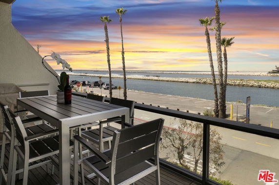 Balcony view overlooking a waterfront and scenic sunset.