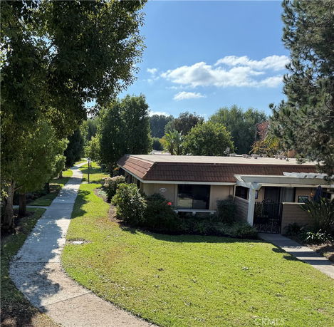Front view of a single-story house with a flat roof and surrounding greenery.