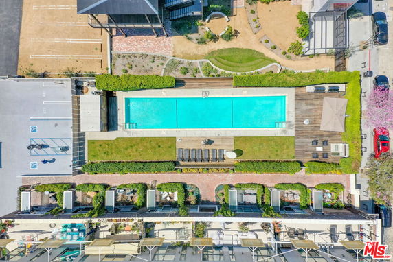 Aerial view of an outdoor swimming pool area with surrounding lounge chairs and landscaping.