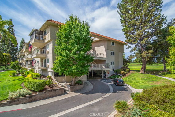Front view of a multi-story apartment building with balconies and a well-maintained landscape.