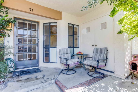 Front view of a house entrance with two chairs and a small table.