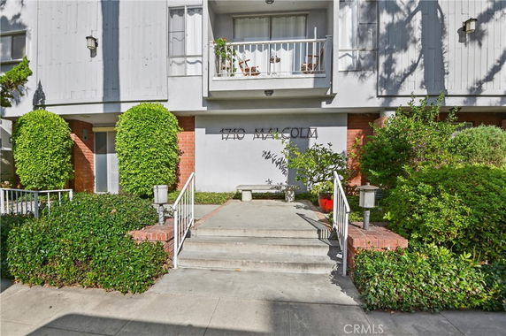 Front view of a multi-story residential building with a small entrance area and balcony.