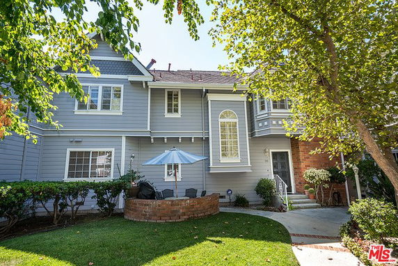Front view of a two-story house with a small patio and umbrella.
