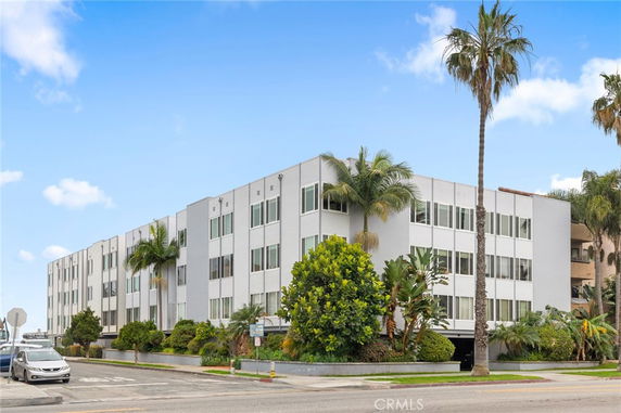 Front view of a multi-story apartment building with palm trees.