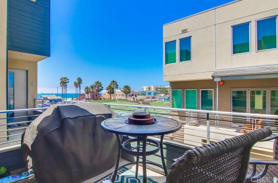 Balcony view with buildings and the ocean in the background.