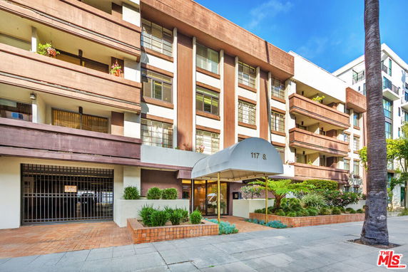 Front view of a multi-story building with balconies and an entrance awning.