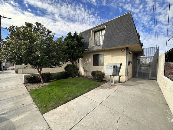 Front view of a two-story building with a sloped roof and small front yard.