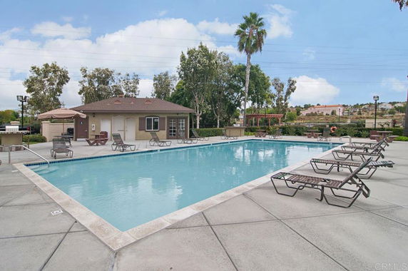 Outdoor swimming pool with lounge chairs and a small building nearby.