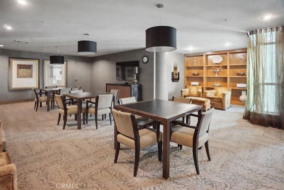 Room with tables, chairs, and shelves in a clubhouse area.