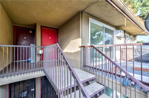 Exterior view of an apartment with a staircase leading to multiple doorways.