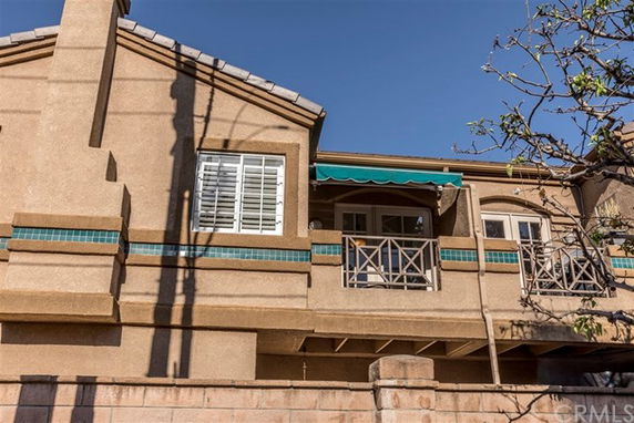 Front view of a multi-story house with a balcony and awning.