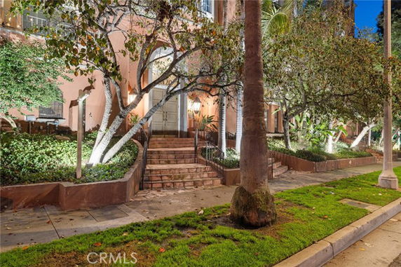Front view of a building with steps leading to the entrance, surrounded by trees and greenery.