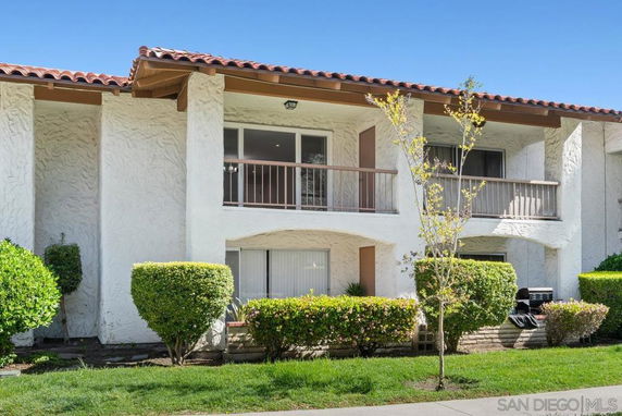 Front view of a two-story building with stucco walls and red-tiled roof.