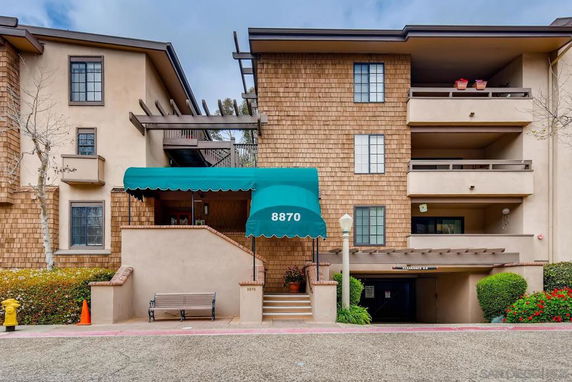 Front view of a multi-story residential building with a green awning entrance.