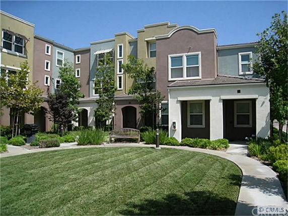 Front view of a multi-story residential building with a landscaped area in front.
