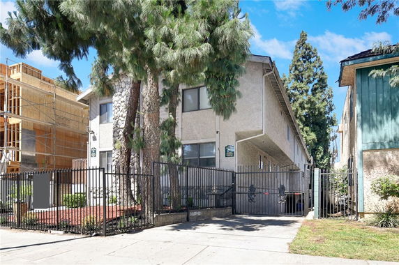 Front view of a two-story residential building with gated entrance and trees in front.