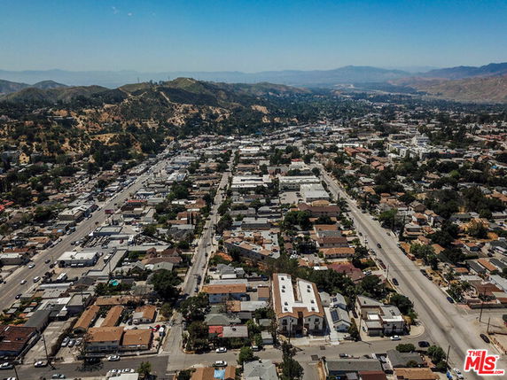 Panoramic view of a suburban neighborhood with houses, roads, and distant hills.