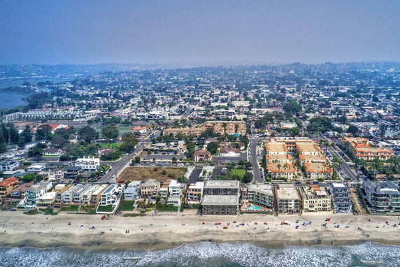 Aerial view of coastal buildings and surrounding urban area near the beach.