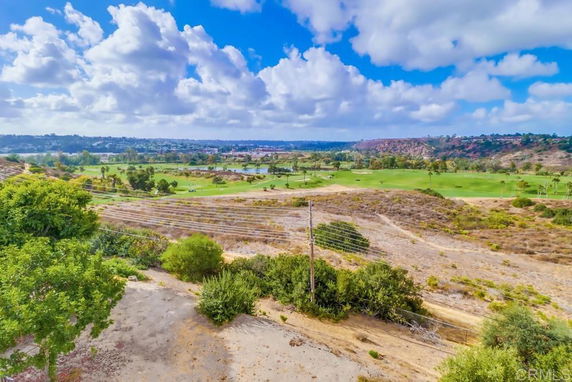 Panoramic view of a landscape with golf course and cloudy sky.