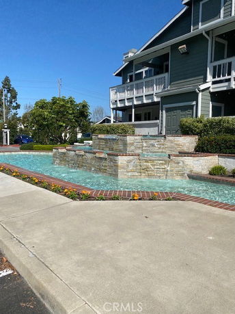 Front view of a multi-story house with a balcony and a decorative water feature.