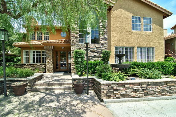 Front view of a house with stone and stucco exterior and a landscaped entrance.