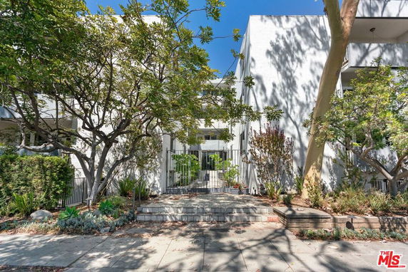 Front view of a contemporary multi-story building with a tree-lined entrance