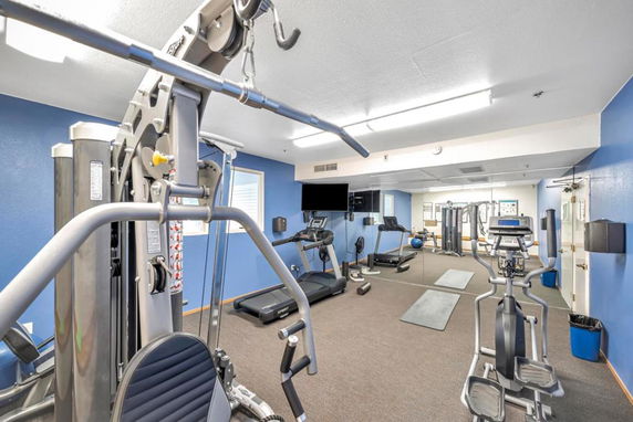 Indoor gym area with various exercise equipment and mirrors.