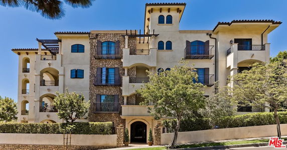 Front view of a multi-story residential building with a stone facade and balconies.