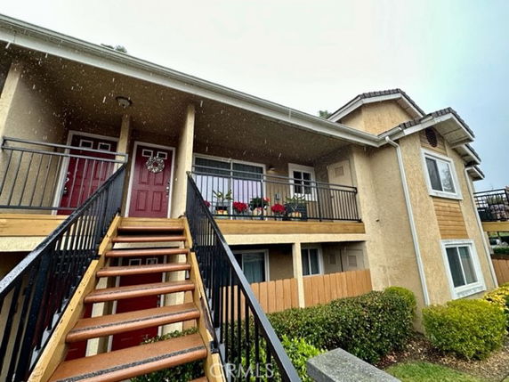 Front view of a two-story residential building with an external staircase and balconies.