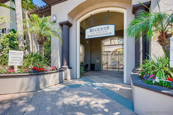 Front elevation of a condominium building entrance with decorative planters and a sign for Regents La Jolla.