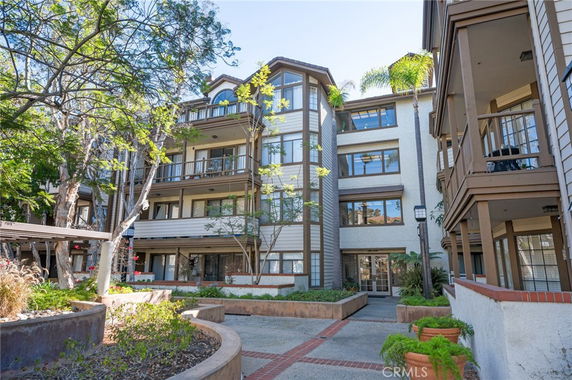 Front view of a multi-story residential building with balconies and surrounding landscaping.