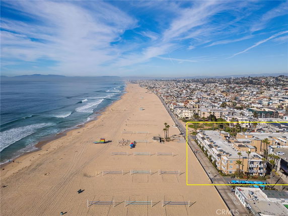 Panoramic view of a coastal city with a beach, ocean, and numerous buildings.