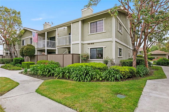 Front view of a two-story apartment building with balconies and landscaping.