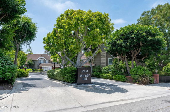 Front view of a house with trees and a gated entrance.