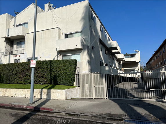 Front view of a multi-story residential building with balconies and gated entrance.