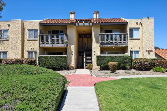 Front view of a two-story apartment building with balconies and a central staircase.