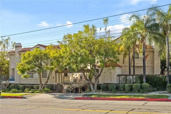 Front view of a two-story residential building with trees and hedges in front.