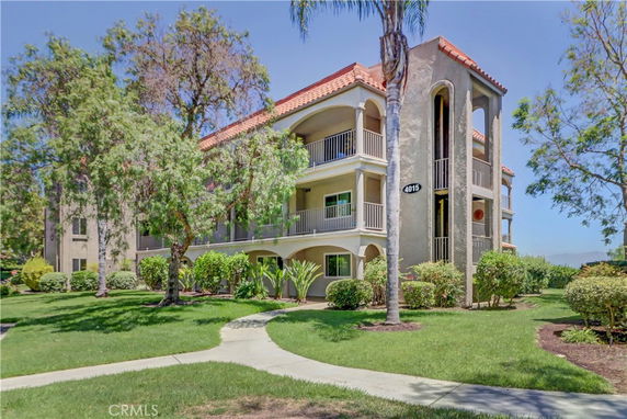 Front view of a three-story apartment building with balconies and orange roof tiles.