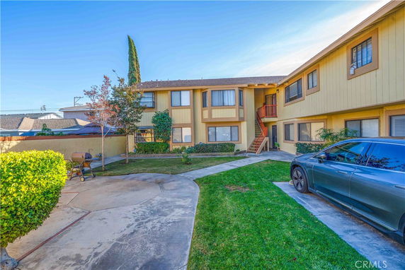 Front view of an apartment building with a central entrance and parking area.