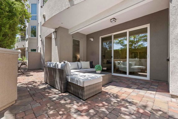 Front view of a modern house with a patio featuring outdoor seating and large windows.