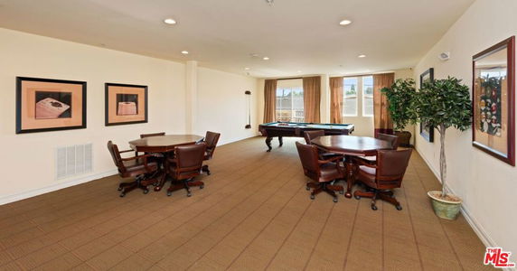 Room with pool table, tables, and chairs in a recreational area.