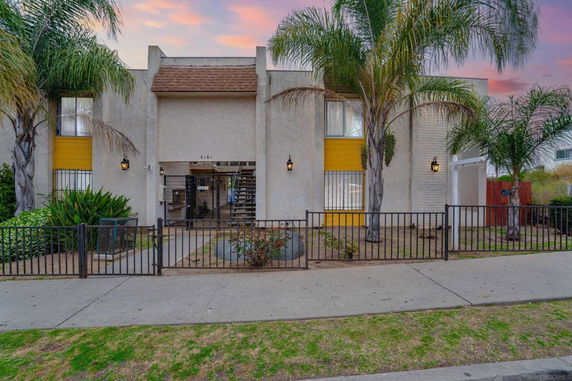 Front view of a two-story building with a central entrance and palm trees.