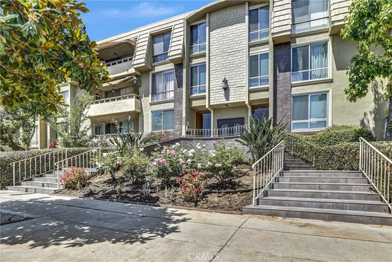 Front view of a multi-story residential building with stairs leading to the entrance.