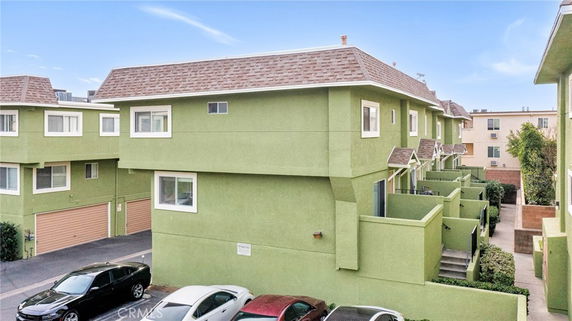 Front view of a multi-story building with green exterior and attached garages.